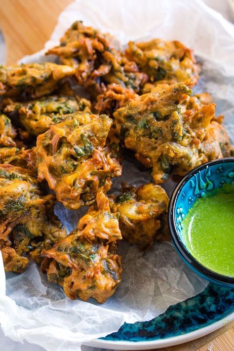 Close up shot of a pile of pakoras served with a small bowl of green chutney. Aloo Pakora, Onion Bhaji Recipes, Vegetable Pakora, Chilli Chutney, Saag Aloo, Street Food India, Onion Bhaji, Bhaji Recipe, Pakora Recipes