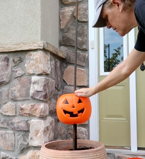 What says fall more than pumpkins? Here is a super easy and inexpensive way to dress up your porch for fall.    Step 1: Get pumpkins  Run, do not walk, to Walmart where plastic pumpkin pails are only $1.00 while supplies last. For one planter, purchase 5 pumpkins.    Step 2: Rebar  Purchase 4' rebar rods and place them into a pot (yellow circles). Secure with stones and soil. I made two planters so I purchased 2 rebar rods and 10 pumpkins.    Step 3: Cut the Handles  We don't need the… Stacked Pumpkins In Planter, Fall Porch Pots With Pumpkins, Fence Post Pumpkins Diy, Plastic Pumpkin Tower Diy, Walmart Pumpkin Crafts, Pumpkin In Flower Pot, Pumpkin Porch Decorations Diy, Pumpkin Outside Decor, Pumpkin Bucket Planter