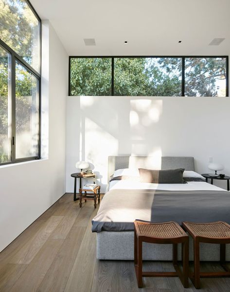 This modern master bedroom has a row of windows above the bed, with a second set of windows adding to the amount of the natural light the room receives. #ModernBedroom #BedroomDesign High Windows In Bedroom, Bedroom High Windows, High Window Above Bed, Bedrooms With Natural Light, Bedrooms With Two Windows, Natural Lighting Bedroom, Windows In Bedroom Ideas, Bedroom Window Above Bed, Ceiling Window Bedroom