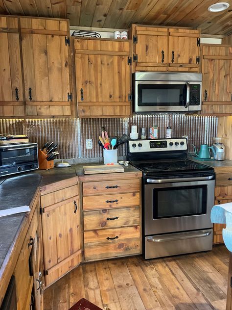 Rustic meets industrial in this kitchen. Pictured: Galvalume ceiling tiles. Farmhouse Kitchen Rustic Cabinets, Barn Tin Kitchen Island, Rustic Kitchen Cupboard Doors, Western Kitchen Countertops, Diy Pallet Cabinets Kitchen, Rustic Kitchen Cabinet Doors, Burnt Wood Cabinets, Rustic House Remodel, Corrugated Metal Wall Kitchen