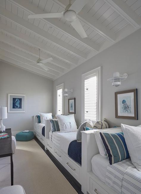 Beach house features a boys' bedroom filled with row of white built-in beds fitted with storage drawers dressed in white and blue striped bedding and pillows lining a single gray wall illuminated by white nautical wall sconces. Beach House Bunk Room, Florida Beach House, Beach House Interior Design, Bunk Rooms, Home Bunch, Bedroom White, Dream Beach Houses, Twin Beds, Classic Gray