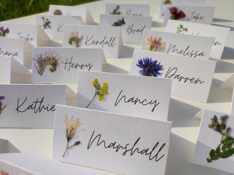 Each card has its own meadow flower, real pressed flower carefully glued on. The cards are already folded and ready to be placed on the table. Perfect for nature inspired wedding, dried flowers wedding, Rustic weddings. White, matte, decorative paper, 250 gsm, is used. You can choose a folded card or a flat card. -The size of a folded card is 9X4.5cm, 3.5X1.7 inches (Full size unfolded 9X9 cm, 3.5X3.5 inches). I can make cards with name and surname. -Flat card size: 9X4.5cm, 3.5X1.7 inches - Tag with golden hole and whatever text you want  size: 10X5 cm, 3.9X1.9 inches.  If you have any special requirements please write to me. Orders over 70 pieces have FREE & EXPRESS SHIPPING. Look here:   https://www.etsy.com/listing/1487518143/pressed-flower-place-cards-with-real?click_key=eca58308b3f2a Wedding Seating Chart Pressed Flowers, Dried Flower Name Card, Pressed Flowers Name Card, Name Cards Table Settings, Fun Place Cards Wedding, Whimsical Place Setting, Name Tag Table Setting, Spring Wedding Name Place Cards, Wedding Invitation With Dried Flowers