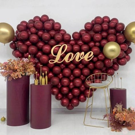 Set the perfect romantic backdrop for your special event by clustering burgundy balloons together in a heart shape. Place a ‘Love’ sign in the center as the focal point of the backdrop while accenting it with classy gold balloons to add some glimmer. Place an arrangement of orchids, roses, and chrysanthemums atop a burgundy column stand & on the floor for added texture while completing the look by placing some sleek gold candle holders atop pedestal pillars for added visual appeal. Heart Shaped Balloon Garland, Burgundy Balloons Decoration, Heart Balloon Garland, Burgundy Balloons, Valentine 2024, Wine Colored Wedding, Event Decor Ideas, Party Decorations Table, Just Married Banner