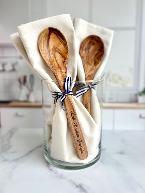 Introducing your new favorite kitchen addition: the Custom-Lake-Name Engraved Olive Wood Spoon and Towel set! This isn't just your average kitchenware - it's a piece of home. Beautifully engraved with your beloved lake, beach, or river name, it's made to bring memories straight into your kitchen. It's a gift that resonates with both men and women, perfect for housewarming or as a lovely hostess present. Imagine commemorating a special time with this personalized kitchen set, made to fit right into your lake house, beach house, or even your cozy little kitchen in the suburbs. Here's what makes this spoon and towel set a cut above the rest: - This custom engraved spoon, carved from Mediterranean olive wood, brings a touch of nature to your kitchen. - The natural (undyed) plain-woven 100% cot Monogram Kitchen Towels, Bridal Shower Hostess Gifts, Wood Spoon Crafts, Hostess Gift Ideas House Guests, Housewarming Gift Ideas For Men, River Name, Towel Gift Ideas, Hummingbird Designs, Small Hostess Gifts