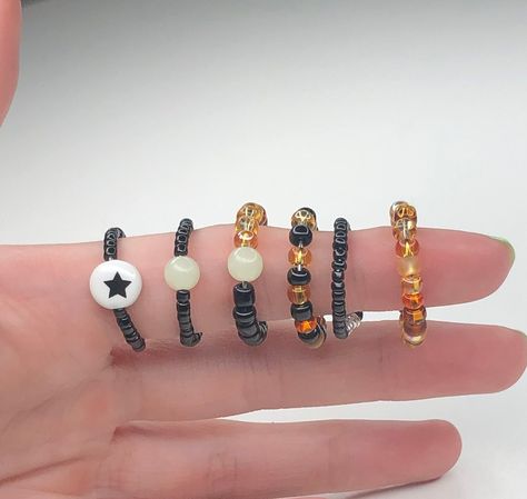 These fall and Halloween inspired rings are a fun statement accessory to add to your jewelry collection. Personalize it to make your perfect ring using our selection of beads:                                - Glow in the dark beads - Black glass seed beads - Smaller black seed beads - Assorted orange glass seed beads - Star bead If you like the necklace shown here is the link:  https://etsy.me/3EQroJB Glow In The Dark Beads, Halloween Ring, Fall Rings, Halloween Beads, Fall And Halloween, Black Seed, Halloween Jewelry, Glass Seed Beads, Stackable Ring