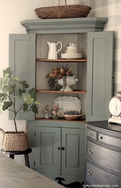 This primitive corner cabinet has been in my family for generations and is over 100 years old! I recently painted it and love how it turned out. #hymnsandverses #antiquecabinet #antiquecornercabinet #paintedcabinet #greencabinet #greenpaint #shadesofgreenpaint #paintingfurniture #furniturepainting #paintedfurniture #primitivefurniture Corner Cabinet Hutch, Corner Cupboard Decorating Ideas, Corner Hutch Kitchen Cabinet, Redone Corner Cabinet, French Country Corner Cabinet, Vintage Cabinets Living Room, Corner Kitchen Cabinet Decor, Corner Cabinet For Dining Room, Dining Room Corner Hutch