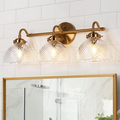 Enhance the atmosphere of your sophisticated bathroom, living room, or bedroom with our stunning 3-light dimmable bathroom vanity light. The captivating electroplated brass finishes seamlessly complement the textured dome glass shade, introducing a modern luxury feel to your cozy spaces. Elevate the aesthetic with Edison bulbs, incandescent, or dimmable LED bulbs, allowing you to customize the brightness to your preference. Please be aware that bulbs and a dimmer are not included, providing you Antique Brass Bathroom Vanity Lighting, Best Brass Vanity Lights, Powder Room Brass Lighting, White Bathrooms With Brass Fixtures, Above Mirror Bathroom Lighting Brass, Country Bathroom Vanity Lights, Bathroom Light Fixtures Over Mirror Traditional, Traditional Over Mirror Bathroom Light, Classic Vanity Lights Bathroom