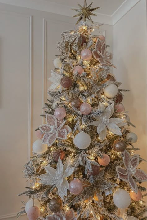 Blush pink Christmas tree with pink baubles white baubles gold tree topper star and pink, white and gold poinsettias on a snowy flocked Christmas tree Light Pink And Champagne Christmas Tree, Xmas Tree With Pink Ornaments, Christmas Tree Rose Gold And White, Pink And Silver Xmas Tree, Blush Christmas Tree Decorations, Blush Ornaments Christmas Tree, Dusty Rose And Gold Christmas Tree, White Gold And Pink Christmas Tree, Blush Pink And Gold Christmas Decor