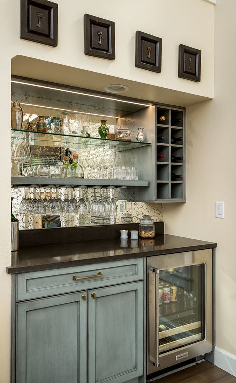 The wine bar / beverage nook is a super convenient home feature typically built between the kitchen and living room, making it much easier to wet your whistle. This one has a chiller (or mini-fridge) a wine rack, and glass shelving backed by a mercury glass mirror. Wine Bar With Mirror, Bar Ideas For Home With Mirror, Bar Space Ideas, Home Liquor Bar Ideas, Wine Nook Ideas Small Spaces, Beverage Bar With Mini Fridge, Drinks Bar Ideas Home, Am Pm Bar, Bar Mirror Ideas