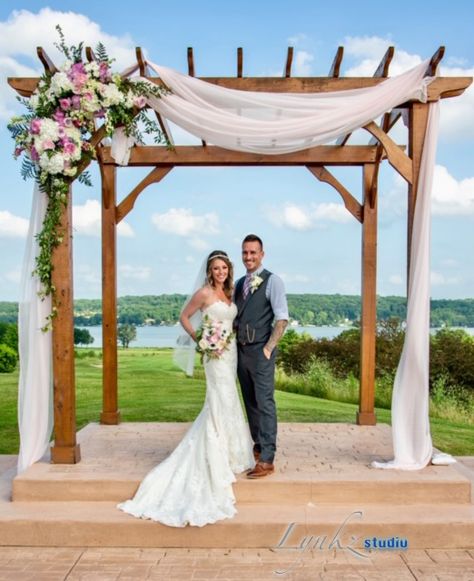 pergola with arrangements and blush chiffon drapes Wedding Pergola Draping, Pergola Ceremony Decorations, Decorating A Pergola For A Wedding, Pergola Drapes Wedding, Wedding Pergola Decorations Outdoor, Wedding Pergola Decorations Draping, Pergola Wedding Ideas, Wedding Pergola Ideas, Wedding Ceremony Pergola