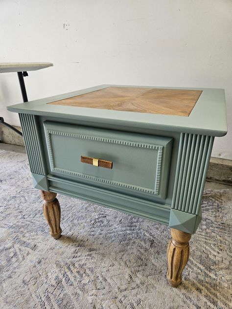 Beautiful vintage table refinished with modern accents.  Sage Green Natural wood Gold Accents New Hardware 1 drawer White and gold leaf lining in drawer Natural wood legs highlighted with custom finishing Measurements: 24" Tall,  28" deep,  26" wide Delivery available within 50 miles of Forty Collins for an additional fee. Message me for arrangements Vintage Phone Table Makeover, End Table Refurbish, Side Table Flip Ideas, End Table Flip Ideas, Side Table Refurbish Ideas, Vintage Nightstand Makeover, Refurbished Night Stand Ideas, Vintage End Table Makeover, Painting Old Furniture Ideas