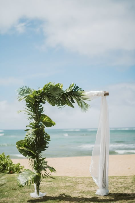 Ceremony arch with leaves and soft white fabric. Simple but elegant. Cherished in Hawaii Weddings Photo by: Christie Pham Photography Wedding Arch Palm Leaves, Wedding Arch With Palm Leaves, Hawaii Wedding Arch Ideas, Hawaiian Wedding Arch Ideas, Palm Arch Wedding, Tropical Wedding Photo Backdrop, Palm Leaf Bouquet Wedding, Tropical Wedding Arbor, Simple Hawaii Wedding