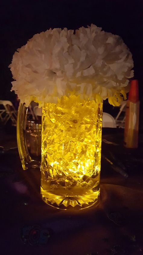 Beer centerpiece.  Cubes from M2 polymer. LED submersible from Amazon. Mug from Dollar Tree. 7 silk carnation. Foam piece for carnations. Beer Mugs Centerpieces, 40th Bday Table Centerpieces, Simple Mens Birthday Decorations, Beer Glass Centerpiece, Cheers And Beers Centerpiece, Beer Mug Centerpiece Table Decorations, Modelo Beer Centerpieces, Cheers And Beers 50th Birthday Party, Cheers To 60 Years Centerpieces