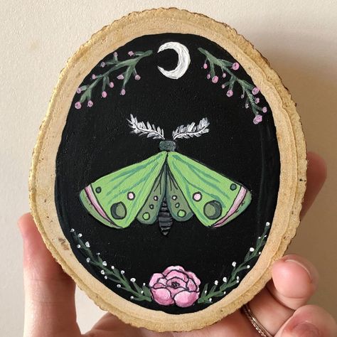 Autumn Woods Studios on Instagram: “A mini moth wood slice painting 🌙 I used to love green and pink when I was younger.. it’s a slept on color combo in my opinion 🌿🌸 . . . .…” Witchy Wood Slice Painting, Mini Wood Paintings, Paint On Wood Ideas, Log Painting Ideas, Witchy Painting Ideas, Wood Painting Ideas, Moths Art, August Leo, Wood Slice Painting