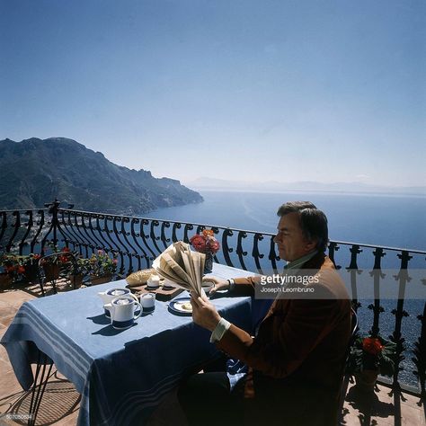 American author Gore Vidal sitting at table on the terrace of his Italian villa overlooking the ocean, reading the newspaper, with breakfast items in front ... Ocean Reading, Reading The Newspaper, Sitting At Table, Gore Vidal, Reading Newspaper, Model Sailboat, Iwo Jima, Italian Villa, Historical Novels