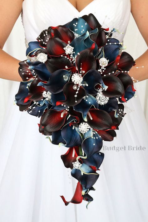 This brides’ bouquet is the perfect option if you have chosen a classic theme for your wedding. A lovely array of burgundy and navy blue calla lilies are center-stage in this stunning arrangement. This bouquet is made with burgundy calla lilies, navy blue calla lilies accented with white pearls, and stunning jewels. As always, this bouquet has been wired by hand and designed by our in-house florists - you can rest assured that our bouquets will maintain their quality and stand the test of time f Burgundy And Navy Blue, Bridal Wedding Flowers, Artificial Wedding Flowers, Bride's Bouquet, Blue Wedding Bouquet, Floral Creations, Rose Boutonniere, Brides Bouquet, Lily Bouquet