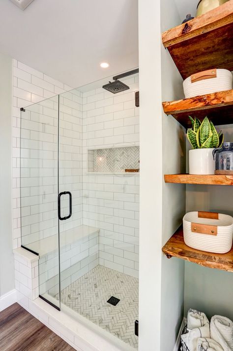 As the focal point of the room, a  freestanding bathtub sits below a large window providing natural light. With the large double vanity, makeup vanity, and exposed shelves, there is no shortage of storage. The beautiful tile shower boasts a tile accent design on the floor and in the niche, and a convenient bench is enclosed in a sleek glass shower door. Shiplap walls, matte black fixtures, and wooden accents are small touches that really bring it all together. Shower With Side Storage, End Of Shower Storage, Shower No Tub Ideas Bathroom, Bathroom With No Bathtub, Walk In Shower With Storage, Shower Next To Closet, Glass Shower In Small Bathroom, Bathroom Decor With Glass Shower Doors, Shower With Side Shelves