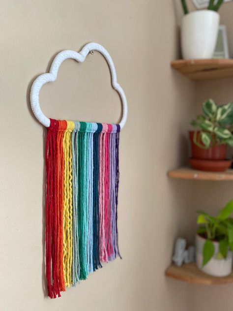 Rainbow cloud wall hanging Eco friendly materials Do you want to bring some fun, boho flair to your nursery? Look no further than this vibrant macrame rainbow cloud wall hanging! Handmade with recycled cotton in a stunning rainbow colour palette, it's the perfect way to add a splash of colour to your little one's space. This rainbow cloud hanging, nursery wall decor, is made using a wooden cloud cutout (from another small business), wrapped in white recycled cotton cord, with rainbow hanging cor Classroom Ceiling Decorations, Rainbow Colour Palette, Rainbow Decor Bedroom, Cloud Hanging, Rainbow Room Decor, Rainbow Macrame Wall Hangings, Cloud Decor, Simple Wall Paintings, Rainbow Lamp