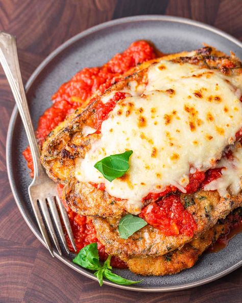 Chicken eggplant parmesan combines two iconic Italian-American dishes. Golden fried chicken cutlets are layered with marinara sauce, fried eggplant slices, Parmigiano Reggiano, and mozzarella.  Perfect for those nights where you can't decide between chicken or eggplant parm! #eggplantrecipes #chickenparm #eggplantparm #chickenandeggplantrecipes #chickendinner Eggplant Parmesan With Chicken, Chicken Eggplant Parmesan Recipe, Eggplant And Chicken Parmesan, Chicken And Eggplant Parmesan Casserole, Chicken Eggplant Recipe, Eggplant With Chicken Recipes, Chicken Eggplant Parmesan Baked, Egg Plant And Chicken Recipes, Eggplant And Chicken Recipes