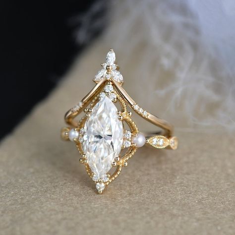 2ct Marquise Moissanite Pearl Engagement Ring Set Yellow Gold Moissanite Chevron Band Vintage Bridal Set 2pcs Flower Halo Ring art deco Milgrain * Ring Material: solid 14k white gold, rose gold, or yellow gold  * Center Stone: Colorless Moissanite   5x10mm, about 1ct   6x12mm , about 2ct    7x14mm, about 3ct * Side Stone: Colorless Moissanite, Natural Pearls, about 0.28ct * Bandwidth: 1.6mm 2-3 WEEKS PROCESSING TIME MADE IN US * Shipping * FREE SHIPPING WITHIN THE USA! * Certificate * All the it Engagement And Band Set, Moissanite Engagement Ring Art Deco, Pearl Engagement Ring Set, Marquise Moissanite Engagement Ring, Pretty Engagement Rings, Milgrain Ring, Moissanite Engagement Ring Set, Flower Halo, Pearl Engagement Ring