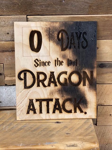 "It's only been zero days since last dragon attack! This wall sign would look perfect in any game room. Your companions should know that dragon attacks are a real thing to look out for... especially on game night! Burned edges and claw marks give it a little authentic feel. Your workplace sign will be 10x12\". Stay aware of workplace dangers! *each sign will be slightly different. Scratches and burn marks are random dragon markings." Dnd Decorations Diy, Mtg Game Room, Dnd House Decor, Dnd Gift Ideas Diy, D&d Room Decor, Dnd Game Room Ideas, Nerd Decor Home, Dragon Halloween Decorations, Dungeon Room Ideas