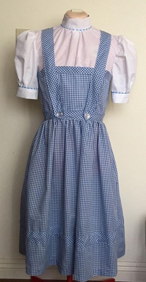 This dress is made to order from a polyester/cotton blend of white and blue gingham fabric. White blouse is trimmed with blue ric rak on the sleeves and collar. Front and back straps are sewn to dress, fastened with large white buttons. "Grow stripe" is included into the skirt for authenticity to the dress Auntie Em would have made for Dorothy. Dress zips up the back and closes with silver hook and eye closure. Dorothy Dress, Not In Kansas Anymore, Dorothy Costume, Dorothy Wizard Of Oz, Blue Gingham Dress, Farm Dress, Dorothy Gale, Vintage Hollywood Glamour, Gingham Fabric