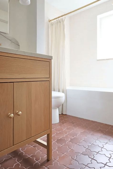 a modern white bathroom with a tub and a window, a terracotta tile floor, a stained vanity and white appliances Terracotta Tile Bathroom, Star And Cross Tile, Modern Mediterranean Bathroom, Bathroom With A Tub, Cross Tile, Terracotta Tile Floor, Small White Bathrooms, Herringbone Tile Floors, Modern White Bathroom