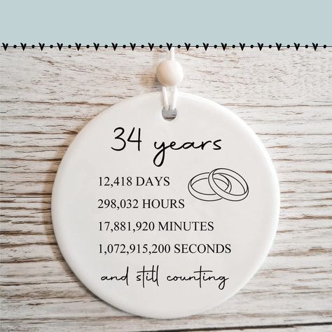 PRICES MAY VARY. 34th Anniversary Ornament: It is a romantic and lasting way to celebrate married years together. Product details: Made of premium white ceramic with a flawless glossy glaze, diameter 2.87 inches, printed with: 34 years, 12,418 days, 298,032 hours, 17,881,920 minutes, 1,072,915,200 seconds and still counting Modern printing technology: All words and images are permanently fused to the surface of this ceramic ornament (this is NOT a decal) and will not peel, crack or fade. Double side printing: The image also appears on the back of the ornament so however it hangs it can be seen. Christmas tree and car decoration: Beautiful addition to the Christmas tree in years to come and it's cute decoration to be hanged into the car rearview mirror Anniversary gifts for couple Pottery Anniversary Gift For Him, Bronze Wedding Anniversary, 10th Wedding Anniversary Gift, 1st Wedding Anniversary Gift, Marriage Gift, Bronze Wedding, 10 Year Anniversary Gift, 6th Wedding Anniversary, Anniversary Ornament