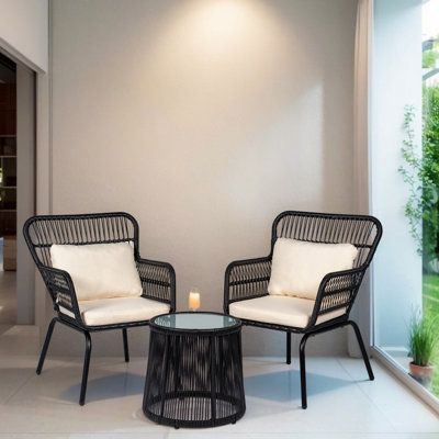 This Outdoor Wicker 3 Piece Bistro Set includes 2 chairs and a matching table with tempered glass top, made from rust and water-resistant PE rattan and powder-coated steel. it offers you a quiet, cozy space outdoors for any garden, patio, front porch, backyard. | Bay Isle Home™ Dawna 3 Piece Seating Group w/ Cushions black | Outdoor Furniture | C004921975_1950826025_1950826027 | Wayfair Canada Front Of House Seating Ideas, Parisian Patio Decor, Black Front Porch Furniture, Garden Chairs Ideas, Front Patio Furniture, Small Front Porch Seating, Front Porch Chairs Ideas, Black Wicker Patio Furniture, Black Sofa Decor