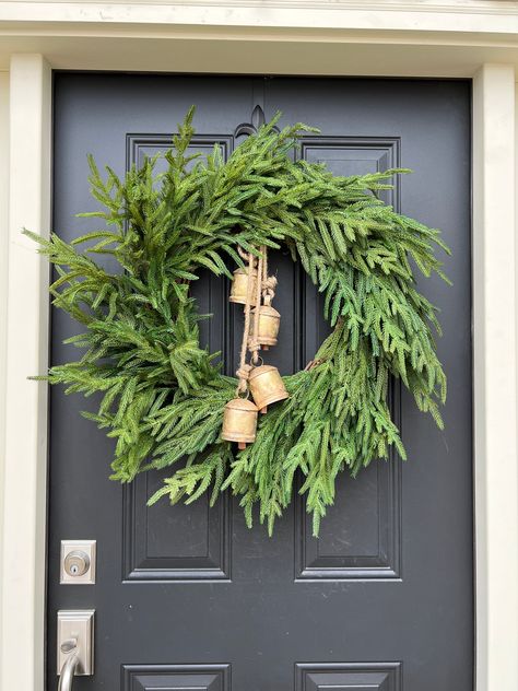 Deck your door with holiday cheer using our Norfolk Pine Wreath, an elegant nod to Christmas traditions. This vibrant green wreath is adorned with rustic bells that softly chime in the winter breeze, calling to mind sleigh rides and carolers at your doorstep. Perfect for those who love the sound of Christmas as much as the sights, this wreath will bring joy and a touch of nostalgia to every visitor. Suitable for both indoor and covered outdoor use. Wreath With Bells And Ribbon, Norfolk Pine Wreath, Outdoor Wreaths On House, Christmas Wreath With Bells, Sleigh Rides, Norfolk Pine, Protection Spray, Hanging Bell, Pine Wreath