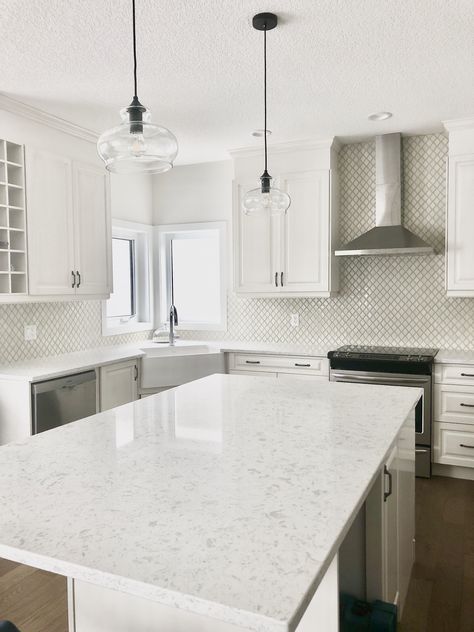 This blend of whites and creams is the perfect combination for anyone who wants a timeless and classic kitchen. #whitekitchen #creamkitchen #whitequartzcountertop #apronsink #whitecabinets #creamcabinets #antiquecabinets #pewterhandles #brightkitchen #farmhousekitchen #highdesignkitchen #arabesquetile #teardroptile #creamtile #raisedpanel #traditionalkitchen #contemporarykitchen #whitewalls #whitecountertops #blackpendants #vintagelights #openconcept #largeisland #marianneelizabethdesign Kitchen White Countertops, Creamy Kitchen, Mosaic Backsplash Bathroom, Cream And White Kitchen, Teardrop Tile, Beach Style Kitchen, Black Cabinet Handles, Transitional Kitchen Design, Custom Backsplash