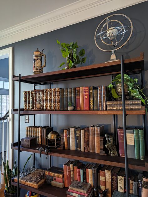 Wall color is apparently "Sherwin Williams Outerspace". Bookcase is apparently "the Beckett Storage Bookshelf from Crate and Barrel". Image originally uploaded at: https://old.reddit.com/r/AmateurRoomPorn/comments/16ju6pj/living_room_with_a_moody_whiskey_bar_vibe_in/ Whiskey Lounge, Living Room Shelf, Storage Bookshelf, Whiskey Room, Room Wall Colors, Room Shelf, Bookcase Styling, Whiskey Bar, Book Room