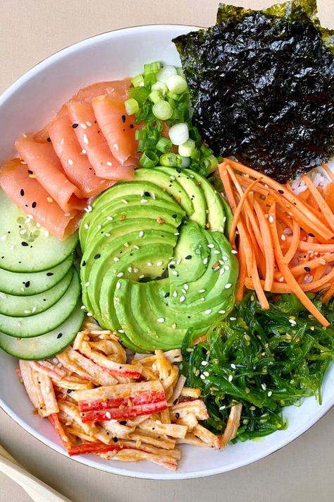 sushi bowl with smoked salmon, spicy mayo crab salad, avocado, cucumber, seaweed, carrots, green onions, and roasted seaweed over white rice and served in a white bowl with a pair of chopsticks Yummy Bowls, Cooking Sushi, Crab Sushi, Salad Bowl Recipes, Sushi Bowl Recipe, Sushi Bowls, Sushi Salad, Easy Sushi, Diy Sushi