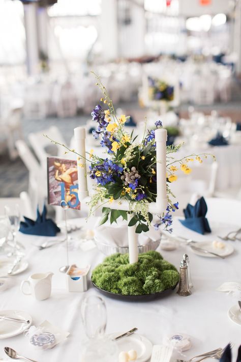 In keeping with the football theme, centerpieces at the reception were goalposts. Ashley's dad made the goals out of PVC pipe. The goals were displayed in moss to resemble the field, and they were decorated with blue and yellow flowers to add a pop of color. Football Themed Wedding Reception, Sports Themed Wedding Reception, Blue Wedding Flower Arrangements, Rugby Wedding, Football Banquet Centerpieces, Penn State Wedding, Ashley Bennett, Blue Wedding Flower, Moss And Flowers