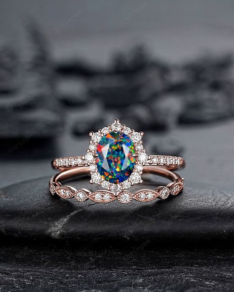 The opal Gemstone is a representative of justice and harmony, and is a protective stone in dangerous places. Opal has always been associated with love and passion, It is a seductive stone that intensifies emotional states and releases inhibitions. It can also act as an emotional stabilizer. Oval Shaped opal and halo moissanite engagement ring with black fire opal main stone and straight band ring set, pictured in rose gold, perfect as a modern wedding ring for a bride to be. Mixed Fire opal wedd Black Opal Wedding Ring, Opal Wedding Set, Unique Gemstone Engagement Rings, Opal Wedding Ring Set, Black Opal Engagement Ring, Fire Opal Engagement Ring, Opal Engagement Rings, Opal Wedding Ring, Lab Black