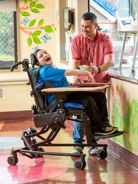 A boy sitting in a Rifton Activity Chair, laughing, with his therapist standing nearby Physio Clinic, Hip Dislocation, Gait Training, Spy Gear, Adaptive Equipment, Disabled Children, Structure And Function, Catch Phrase, Special Needs