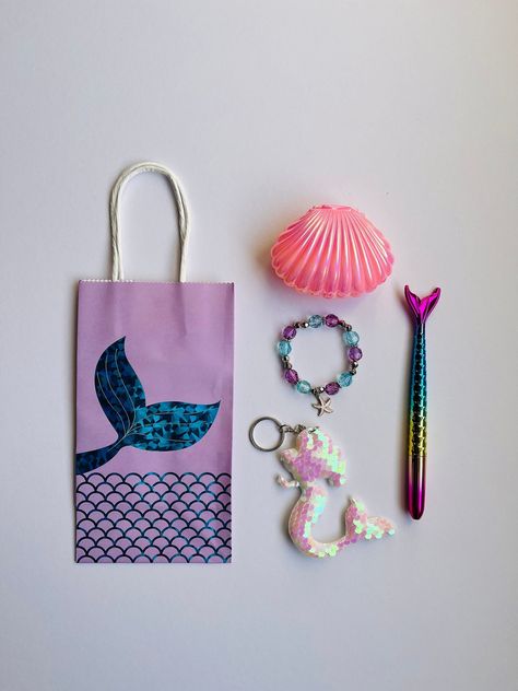 Bring your mermaid or under the sea party to life with this amazing Mermaid Party Bag  The whole set includes: 1 x Mermaid tail paper party bag. Size 10cm wide x 19cm (without handle) 26cm (with handle) tall x 7cm deep.  1 x Pink Shell jewellery box.  1 x Bracelet with starfish pendant. The starfish pendants come in 5 assorted colours: pink, purple, silver, blue, and sea green - see picture 3. 1 x Mermaid tail pen. 1 x Mermaid keyring with sequins. Not suitable for under 3s. The mermaid paper bags can be sold separately. Express Delivery option: For all UK orders made before 2pm, we can despatch on the same business day using Royal Mail special delivery, which guarantees next working day delivery by 1pm. Please choose this option if your order is urgent. Please message us if you have any q Mermaid Birthday Party Loot Bags, Mermaid Party Favours, Mermaid Treat Bags, Mermaid Party Bags, Underwater Party, Paper Party Bags, Mermaid Bag, Mermaid Birthday Party Decorations, Mermaid Party Favors