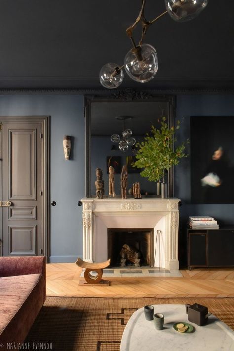 Moody and dark living room with dark blue walls, black trim and doors + light wood herringbone floors + large mirror over the fireplace + modern atom chandelier | Marianne Evennou Blue Walls Living Room, Herringbone Wood Floor, Dark Blue Walls, Dark Living Rooms, French Country Living Room, Ad Magazine, Dark Walls, Trendy Living Rooms, Country Living Room