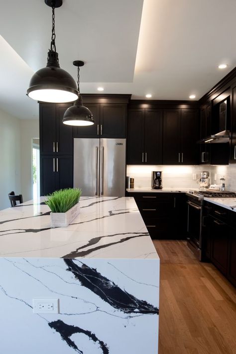 Black kitchens are a popular new design trend we can't get enough of. The black cabinets paired with the marble waterfall countertops make this feel ultra luxurious. Waterfall Countertop Island, Black Kitchen Cabinets Ideas, White Marble Kitchen Island, Black Kitchen Ideas, Black Marble Countertops, Professional Kitchen Design, Marble Kitchen Island, White Marble Kitchen, Interior Design Layout