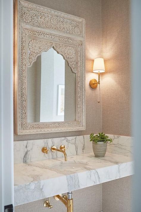 Stunning bathroom design featuring a Moroccan style carved wood vanity mirror lit by Camille Long Sconces on a grasscloth wallpaper wall. Wood Vanity Mirror, White Marble Sink, Moroccan Bathroom, Moroccan Home Decor, تصميم داخلي فاخر, Moroccan Interiors, Aesthetic Bathroom, Stunning Bathrooms, Trendy Bathroom