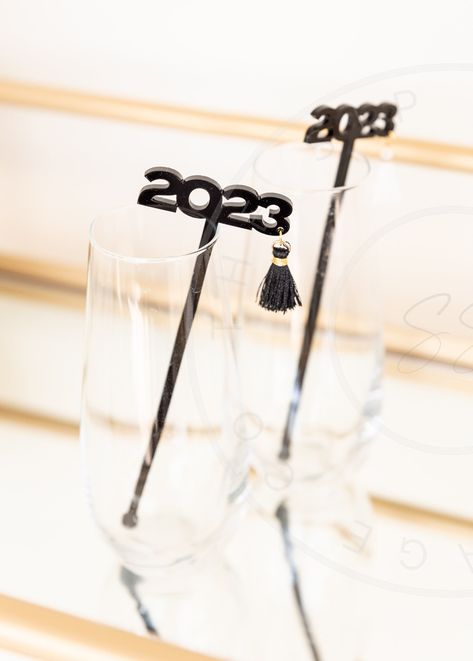 2023 Graduation drink Stir Sticks.   These drink stirrers are perfect addition to any graduation party! Choose your tassel color.  The stirrers are black, We currently offer black and white tassels. We may be able to find a different color upon request.  Stirrers are made with 1/8 in cast acrylic.  Total stirrer length is 6 inches.  If you would like a different length please message me.  if you need a large order please contact me.  Drink stirrers are made to order. Will ship in 2-4 businesses days (does not include weekends) . Larger orders may take longer. Will provide estimated time when order is placed. There is faster shipping options available at check out. Be sure to check out our other drink stirrers! Graduation Party Drinks, Black And White Party Decorations, White Party Decorations, Drink Stirrer, Champagne Drinks, Drink Marker, Drink Tags, 2023 Graduation, Drink Stirrers