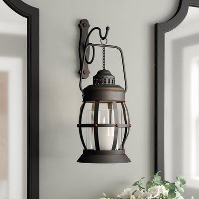 Candlelight might not be as important in our modern, electric world, but that doesn't mean it can't add something to your home today. Take this sconce, for example: taking cues from old world lanterns, this piece is a great option for adding a traditional-inspired touch for your candles. Crafted from black-finished iron with distressed accents, this piece features a central glass candle holder cradled by a lantern grille. Wall-mounted, this piece accommodates candles up to 3'' in diameter. | Thr Iron Wall Sconces, Wood Lantern, Iron Lanterns, Lantern Wall, Iron Candle, Glass Lantern, Metal Candle, Wall Lantern, Iron Wall