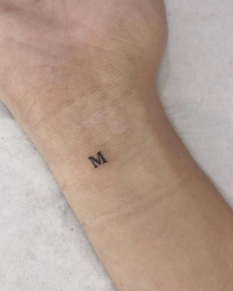 Tiny tattoo of the letter "M" located on the wrist. Tiny Letter Tattoo Wrist, Dainty M Tattoo, Tiny M Tattoo, Small M Tattoo Letter, Initial Tattoo Men, Initial M Tattoo, M And M Tattoo, Tattoo Letra M, M S Tattoo