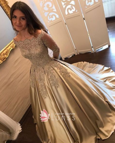 Elegant beaded gold lace off-the-shoulder long sleeve satin formal ball gown. Scalloped off-shoulder neckline. Medium length train. Gold Prom Dresses Long, Gown Couture, Lace Prom Gown, Champagne Gown, Baju Kahwin, Long Sleeve Bridal Gown, Long Sleeve Ball Gowns, Satin Ball Gown, Gold Prom Dresses