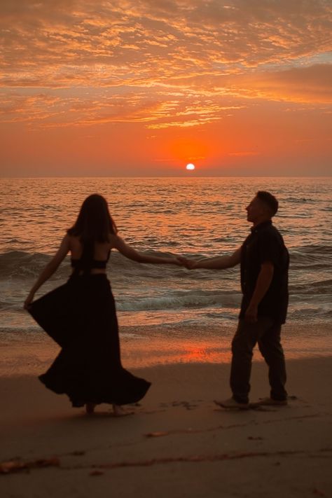 young couple dancing with the sunset to la vie en rose. girl is wearing black dress and boy is in khakis and a dark button up. The sun is setting behind them, spreading a bright orange and pink hue across the sky and into a set of clouds at the very top of the photo.the photo is taken at a beach in La Jolla San Diego California. Sun Set Couple Photos, Couples On Beach Sunset, Sunset Couple Photography Beach Photo Ideas, Beach Nikkah, Sunset Photoshoot Ideas Golden Hour, Sunrise Engagement Pictures Beaches, Golden Hour Beach Engagement Photos, Couples Sunset Photoshoot Beach Photos, Goa Pre Wedding Photoshoot