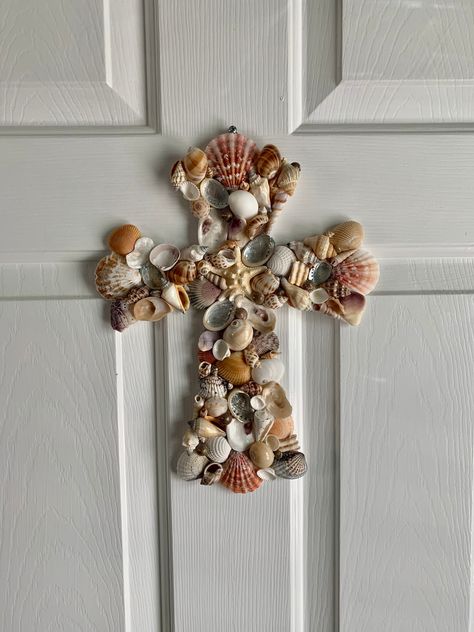 "This beautiful, handcrafted coastal seashell cross is guaranteed to add a tranquil touch to your coastal home wall decor. The cross is adorned with a variety of seashells found along the coast of North Carolina, featuring abalone shells and a starfish at the center.  Measures 12\" l x 9\" w Seashells securely attached with high quality weather resistant glue.  Cross is hand painted white.  Each seashell design varies while maintaining the same style and beauty. Recommended for indoor use or wel Cross With Shells, Cross Room Decor, Seashell Ladies, Sea Shell Crafts Seashell Art, Seashells Crafts, Easter Wreath Cross, Wood Crosses Diy, Seashell Wall Decor, Wooden Cross Crafts