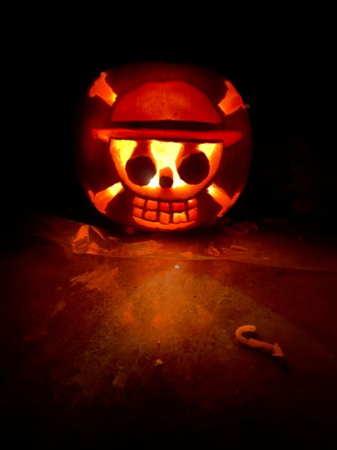 Glowing pumpkin in a dark room with the straw hat luffy logo skull and cross bone Luffy Pumpkin Carving, Pumpkin Anime Carving, Luffy Pumpkin, Naruto Pumpkin Carving, One Piece Pumpkin Carving, Pumpkin Carving Ideas Anime, Anime Pumpkin Carving Ideas, One Piece Pumpkin, Anime Pumpkin Carving