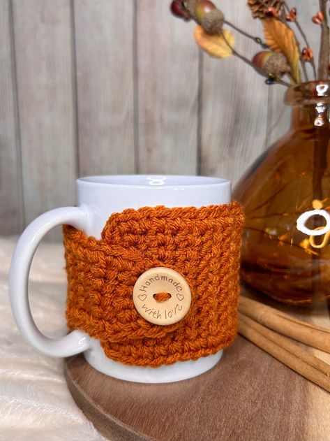 Snuggle up your coffee cup during cozy sweater weather with this handmade pumpkin spice crochet mug cozy. Perfect for 12 oz mugs, it keeps your hands from burning while keeping your drink warm. Plus, the 25mm natural wood button adds a heartfelt touch, saying "handmade with love." It arrives charmingly packaged, perfect for gifting and stuffing into stockings! SIZE: 3" wide x 12.25" longFits 12 oz (3.35"W x 3.94"H) mug Crochet Mug Cozies, Coffee Cup Cozy Crochet Pattern Free, Crochet Materials, Knit Coffee Cozy, Coffee Crochet, Mug Cozy Pattern, Coffee Mug Cozy, Crochet Mug Cozy, Crochet Mug