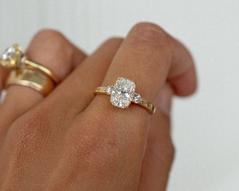 A gorgeous recent custom piece, with a 2.06 elongated cushion cut dimond, 2 round diamond accent stones, set into a low band flat band for a modern feel ✨ Details: - 2.06ct elongated cushion diamond - 2x round diamonds - 18k yellow gold - 2mm wide shank #elongatedcushion #customengagementring #engagementringideas #engagementringdesign #threestoneengagementring #nz #aus Engagement Rings Flat Setting, Elongated Cushion Cut 3 Stone Ring, Cushion Ring Stack, Cushion Elongated Engagement Ring, Engagement Ring Old Money, Small Elongated Cushion Engagement Ring, Cushion Cut Elongated Engagement Ring, Rounded Cushion Engagement Ring, Bezel Elongated Cushion