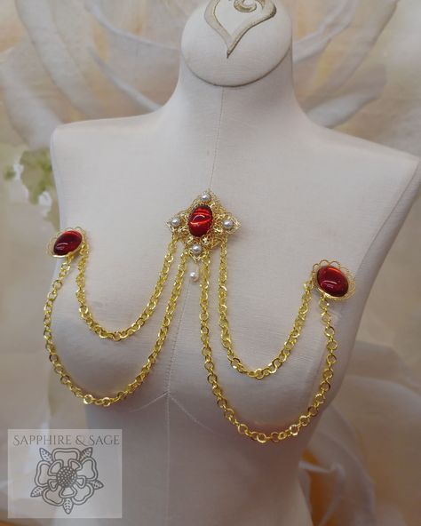 The "Wilhelmina" Swag Bodice Jewelry adds a touch of class to any period ensemble. With its Renaissance-style brooch centerpiece with swags of gold-tone chains connected to smaller brooches in matching colored stones, you'll be sure to shine. Transform your look with a timeless accessory perfect for any occasion. Red And Gold Accessories, Ornamental Jewelry, Shiny Accessories, Bra Chain, Chest Jewelry, Haute Couture Jewelry, Roman Jewelry, Cosplay Jewelry, Light Sapphire